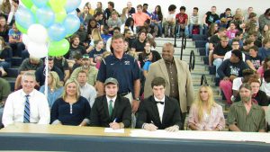 WALTON SENIORS Koleman Truett (left middle) and Danny Hicks (right middle) inked football scholarship offers on Thursday at Walton High School. Truett is off to Ave Maria University while Hicks will attend Huntingdon College. (Photo by Patrick Casey)